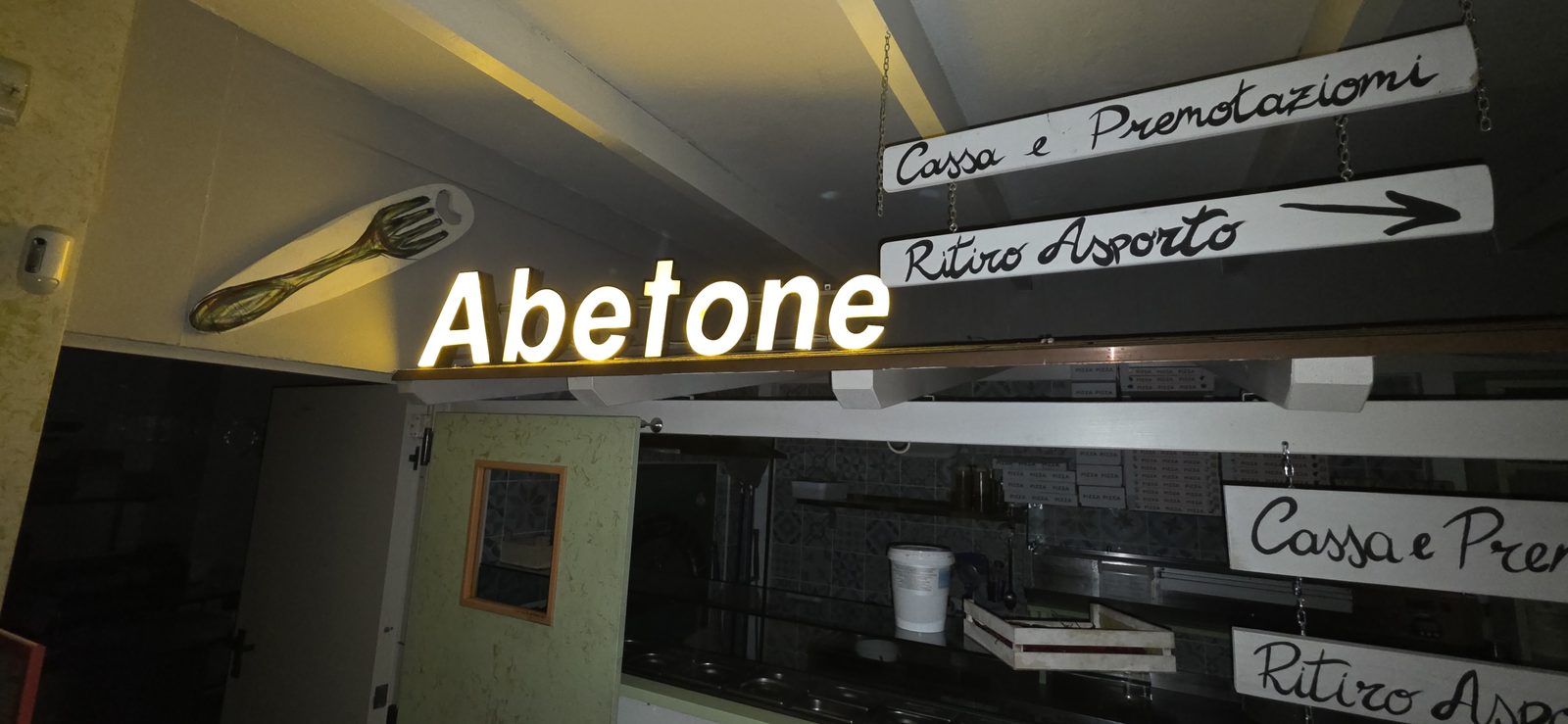 La scritta luminosa Abetone e le insegne Cassa e prenotazioni e Ritiro asporto all'ingresso del Garage