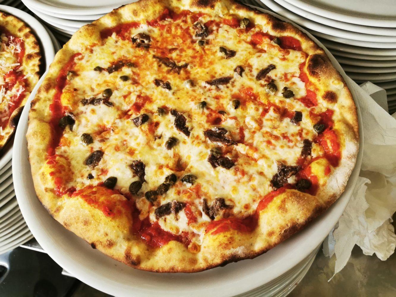 Pizza tonda dal bordo alto appena uscita dal forno a legna