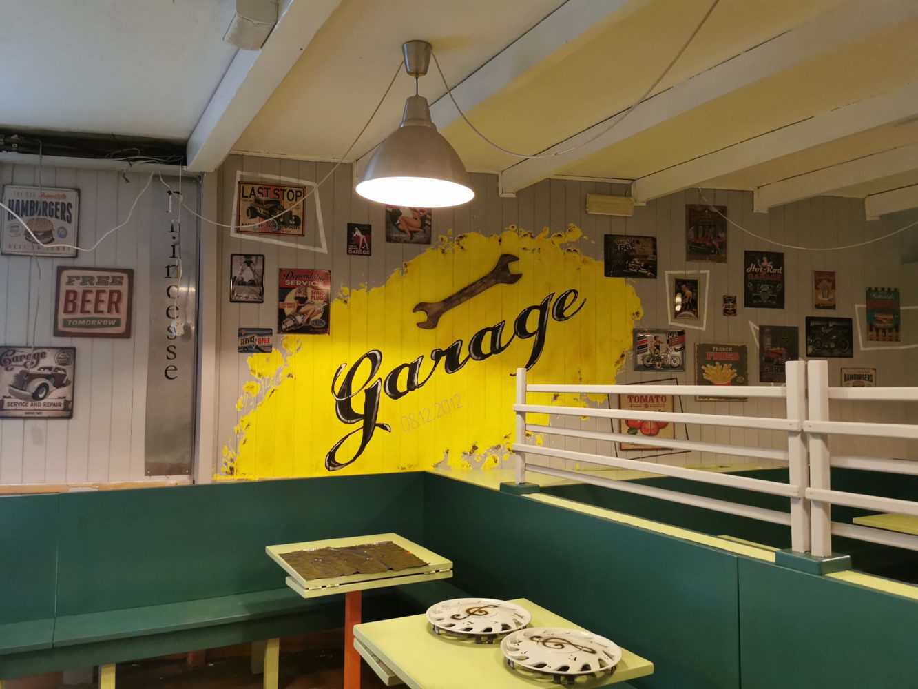 La sala del Garage con il muro giallo, le insegne d'epoca e i tavoli