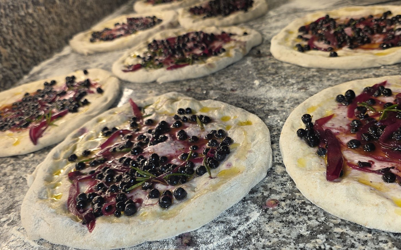 Stiaccino del bosco con mirtilli, cipolla rossa e rosmarino, pronti per il forno a legna, solo d'estate